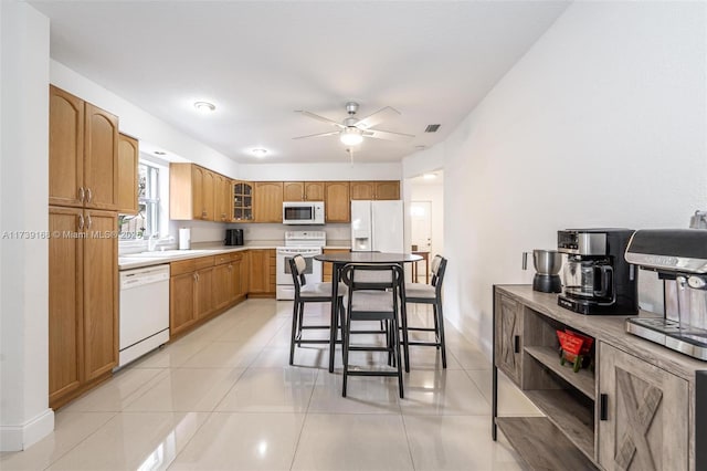 kitchen featuring glass insert cabinets, a sink, ceiling fan, white appliances, and light tile patterned flooring
