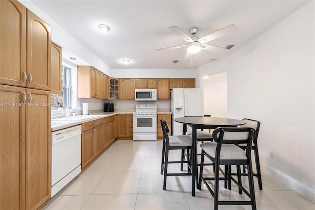 kitchen featuring white appliances, glass insert cabinets, light countertops, light tile patterned floors, and a sink