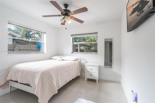 bedroom featuring multiple windows, light tile patterned floors, and ceiling fan