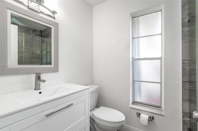 bathroom with vanity, a healthy amount of sunlight, decorative backsplash, and toilet