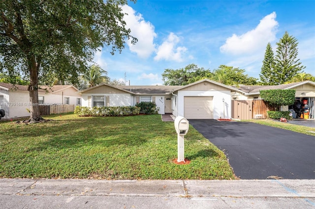 ranch-style home with driveway, fence, a garage, and a front lawn