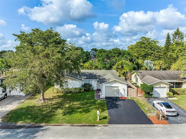 view of front of property with a front yard, a detached garage, fence, and driveway
