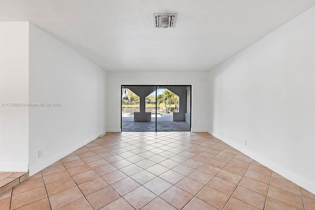 tiled empty room with a textured ceiling