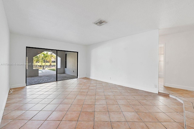 tiled spare room featuring a textured ceiling