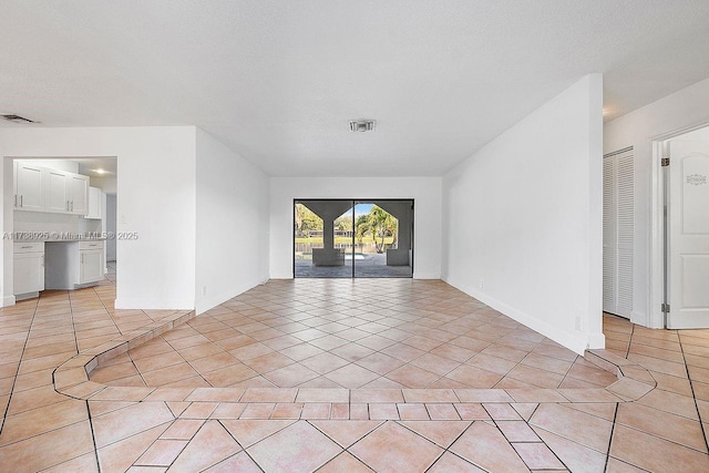 tiled empty room with a textured ceiling