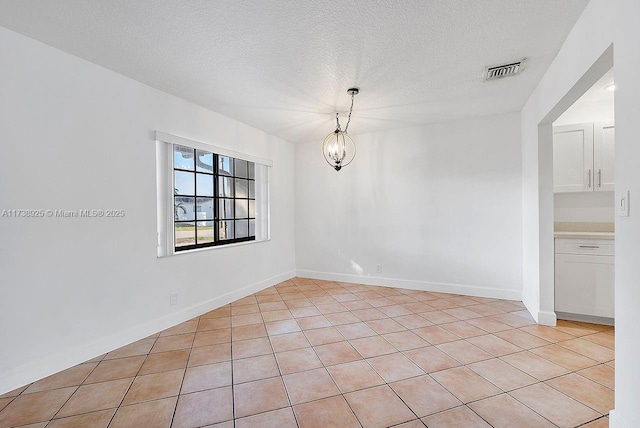 unfurnished room featuring light tile patterned flooring, a textured ceiling, and an inviting chandelier