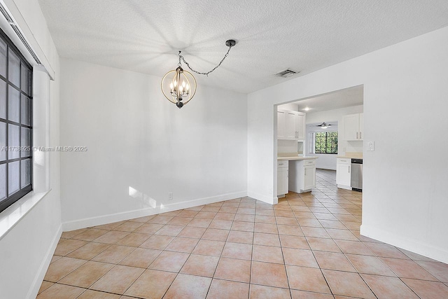 tiled spare room featuring a chandelier and a textured ceiling