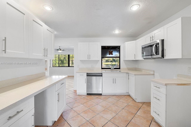 kitchen featuring light tile patterned flooring, appliances with stainless steel finishes, sink, and white cabinets