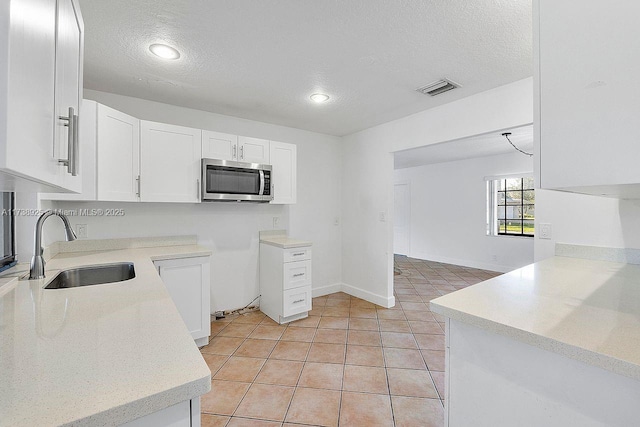 kitchen featuring white cabinetry, sink, a textured ceiling, and light tile patterned floors