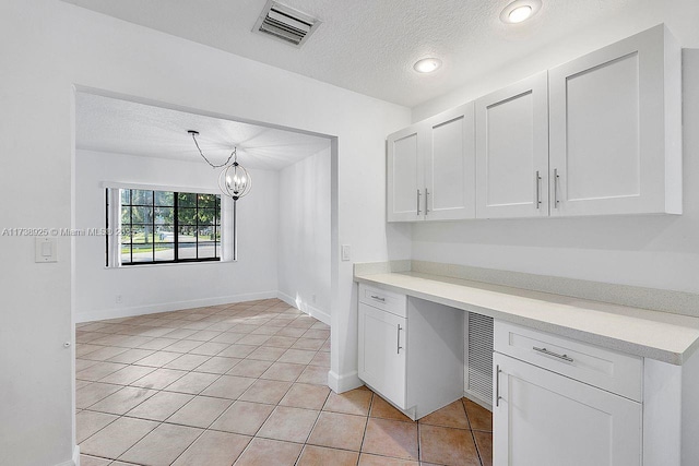 kitchen featuring light tile patterned floors, decorative light fixtures, a textured ceiling, and white cabinets