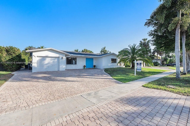 ranch-style house featuring a garage and a front lawn