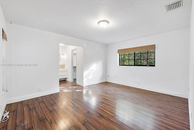 spare room with a textured ceiling and dark hardwood / wood-style flooring