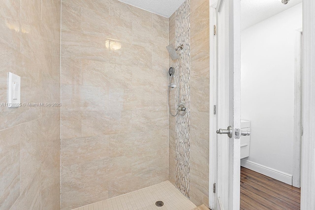 bathroom with tiled shower and wood-type flooring