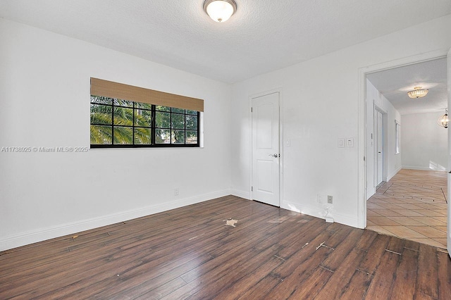 spare room with dark wood-type flooring and a textured ceiling