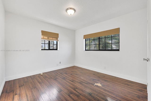 unfurnished room with dark hardwood / wood-style flooring and a textured ceiling