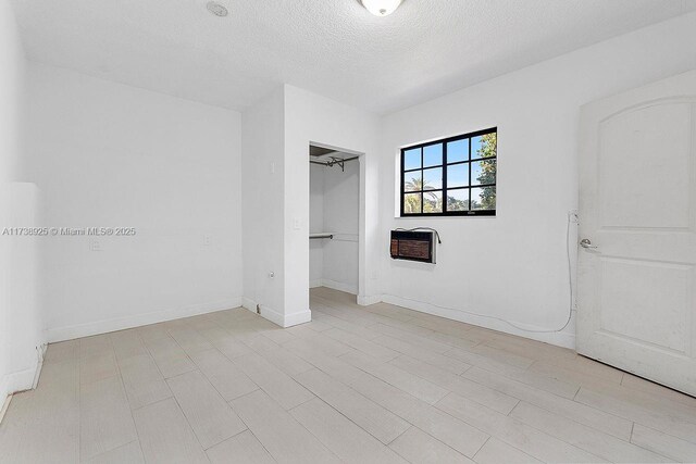 unfurnished bedroom featuring heating unit, a textured ceiling, and a closet