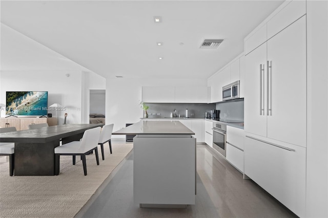 kitchen featuring sink, tasteful backsplash, appliances with stainless steel finishes, a kitchen island, and white cabinets