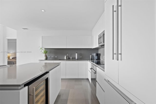 kitchen featuring appliances with stainless steel finishes, tasteful backsplash, sink, wine cooler, and white cabinets