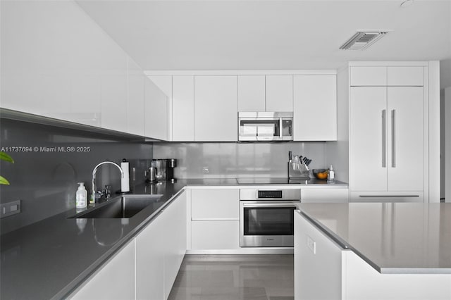 kitchen featuring stainless steel appliances, tasteful backsplash, sink, and white cabinets