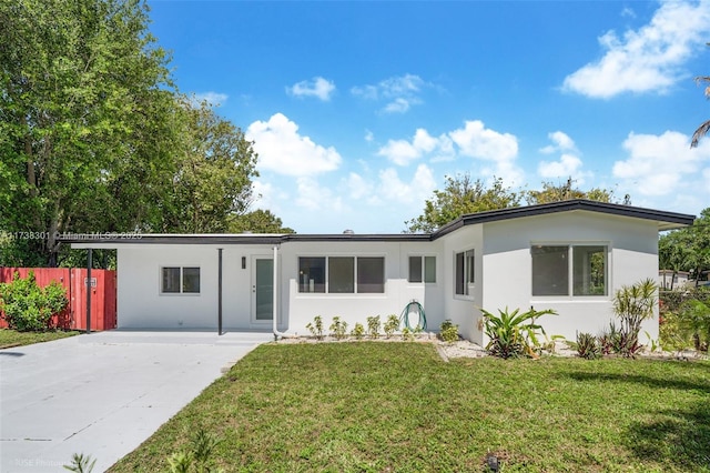 view of front of home featuring a front yard, fence, driveway, and stucco siding