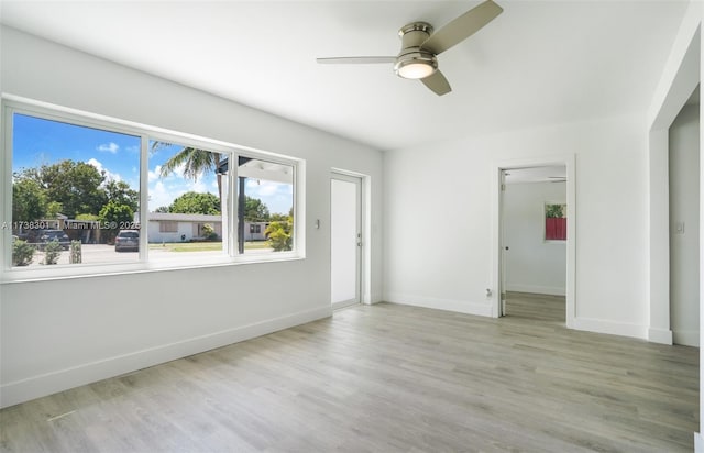 empty room with ceiling fan and light hardwood / wood-style flooring