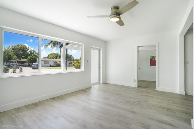 unfurnished room with baseboards, light wood-style floors, and ceiling fan