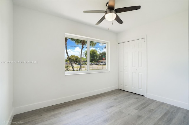 unfurnished bedroom with a closet, baseboards, and wood finished floors