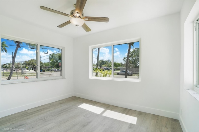 empty room featuring baseboards, ceiling fan, and light wood finished floors