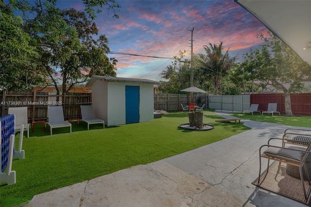 yard at dusk featuring a patio and a shed