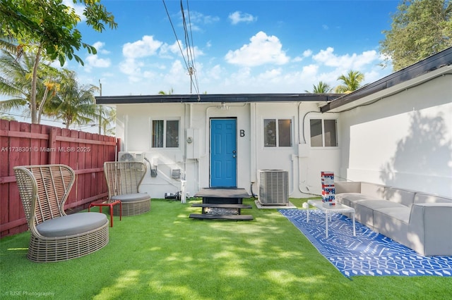 back of property with a yard, central AC unit, stucco siding, and fence