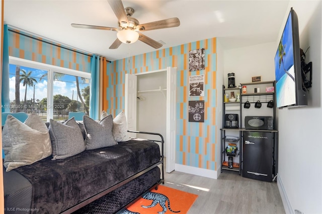 living room with wallpapered walls, wood finished floors, baseboards, and ceiling fan