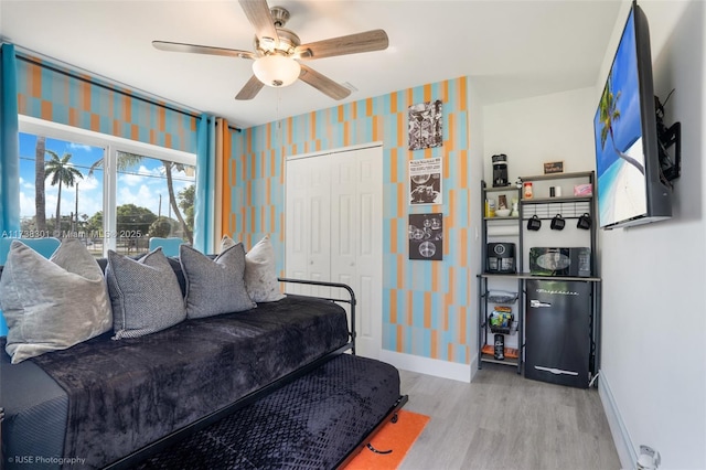 living room featuring baseboards, wood finished floors, a ceiling fan, and wallpapered walls