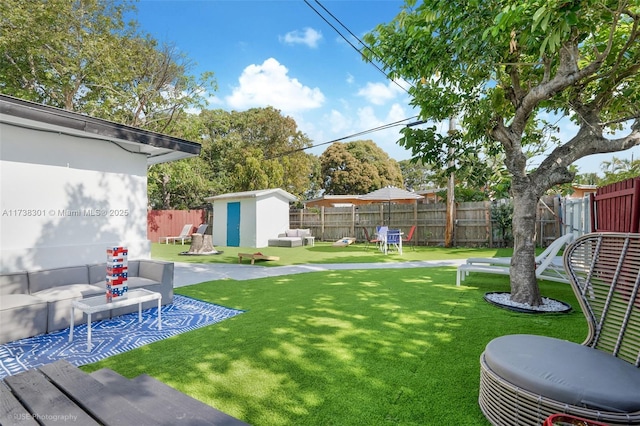 view of yard with an outdoor structure, a fenced backyard, a storage shed, and a patio area