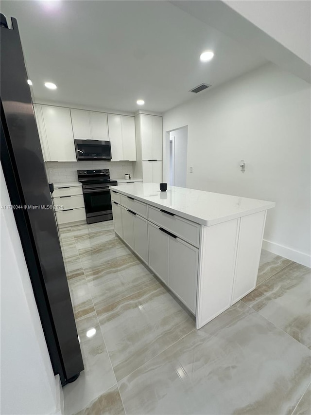 kitchen with black electric range oven, backsplash, white cabinets, and a kitchen island