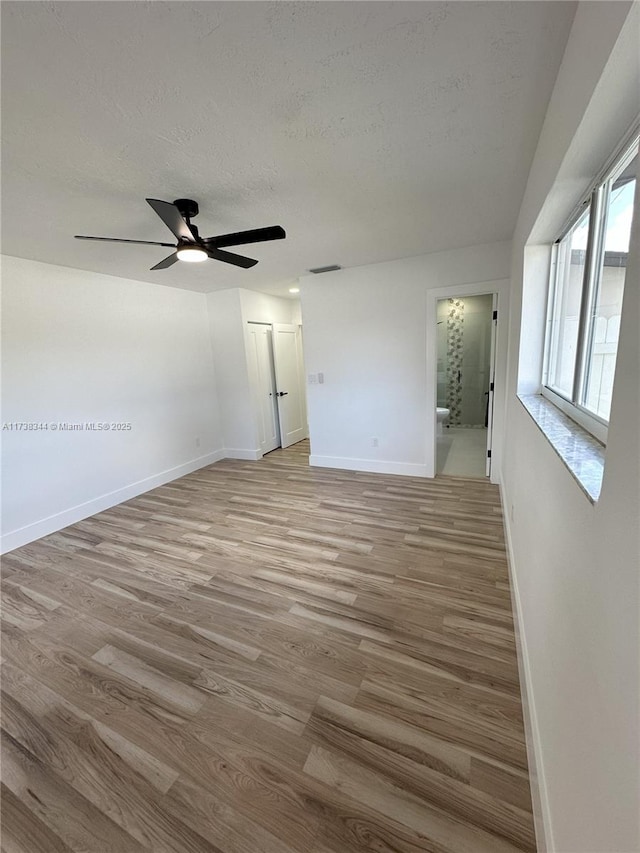 unfurnished room featuring ceiling fan, a textured ceiling, and light wood-type flooring