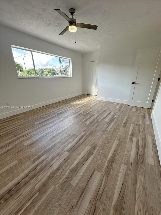 spare room with ceiling fan, a textured ceiling, and light wood-type flooring