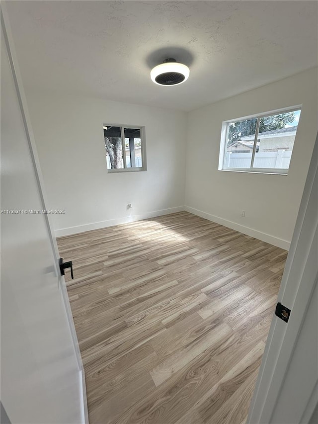 empty room with a textured ceiling and light wood-type flooring