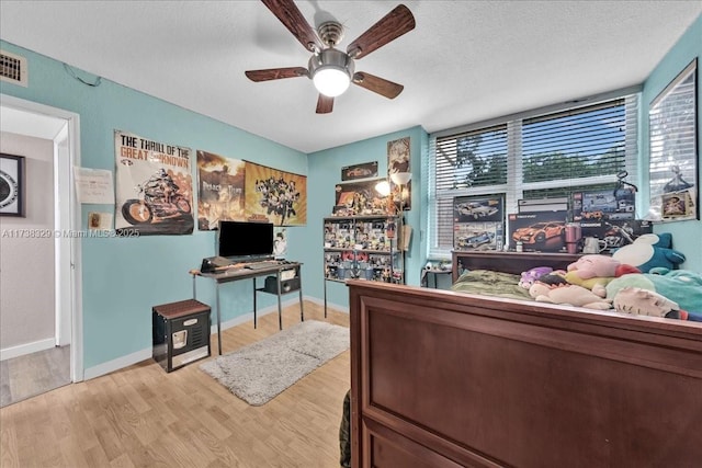 bedroom with ceiling fan, a textured ceiling, and light wood-type flooring