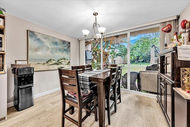 dining room with a notable chandelier, light wood-type flooring, and a wall of windows