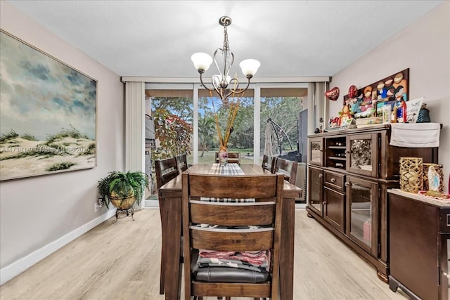 dining area featuring a chandelier, a wall of windows, and light hardwood / wood-style flooring