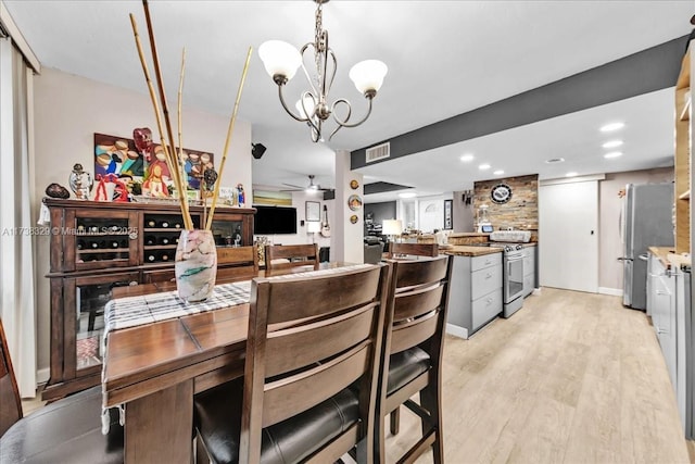 dining area with ceiling fan with notable chandelier and light wood-type flooring