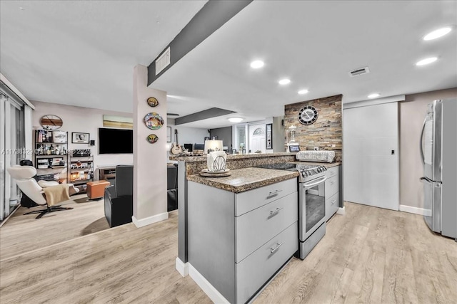 kitchen with appliances with stainless steel finishes, stone countertops, and light hardwood / wood-style flooring