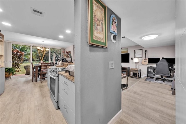 hall featuring an inviting chandelier and light wood-type flooring