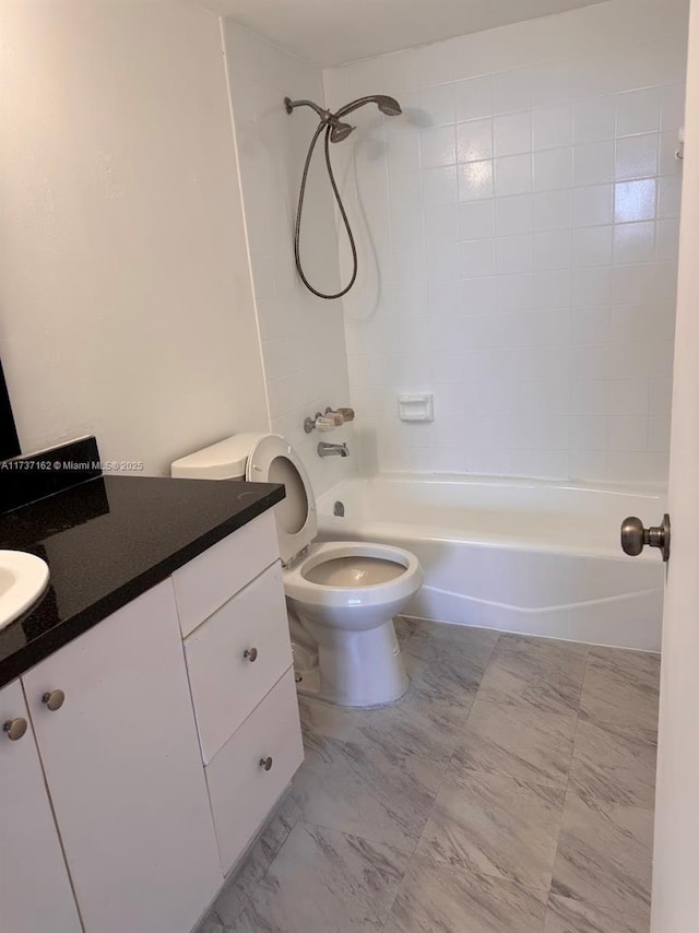 full bathroom featuring vanity, tiled shower / bath combo, and toilet