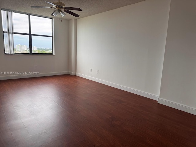 empty room with dark hardwood / wood-style flooring, ceiling fan, and a textured ceiling