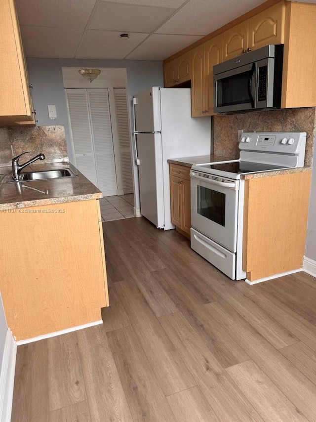 kitchen featuring sink, white appliances, a drop ceiling, light wood-type flooring, and light brown cabinets