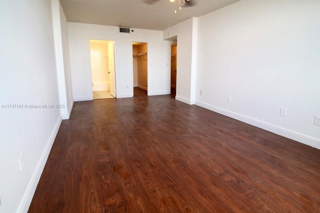 unfurnished bedroom with ceiling fan, a spacious closet, dark hardwood / wood-style flooring, and a closet