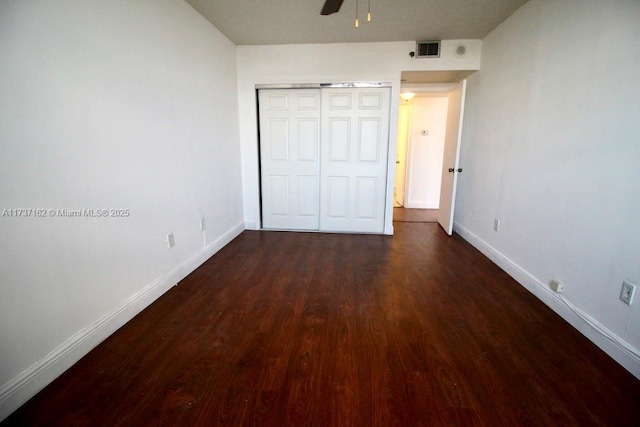 unfurnished bedroom featuring dark hardwood / wood-style flooring, a closet, and ceiling fan