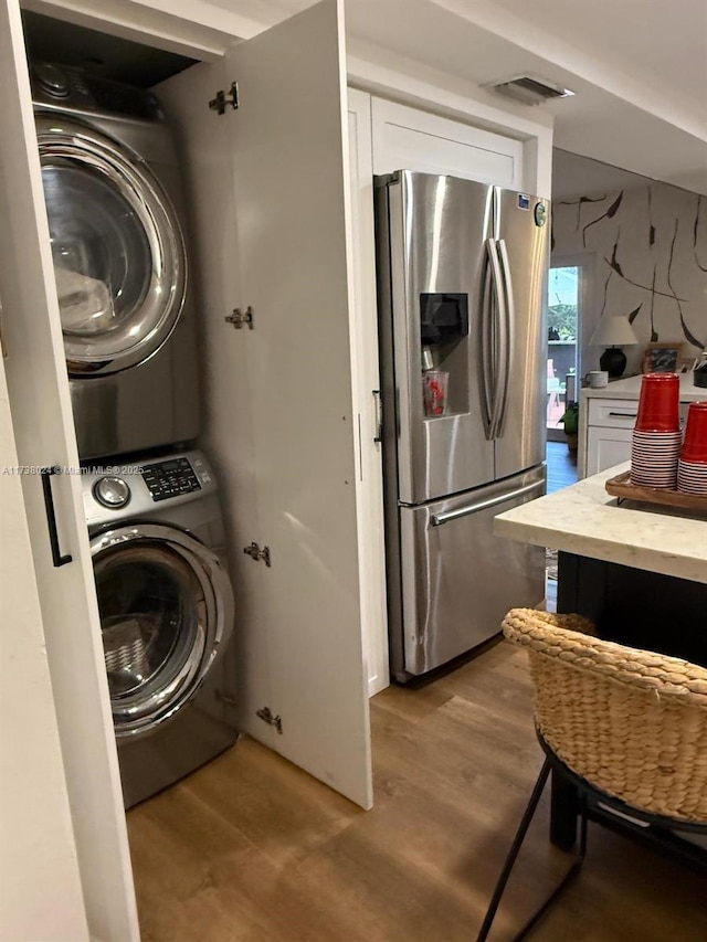 washroom with stacked washer and dryer and light wood-type flooring