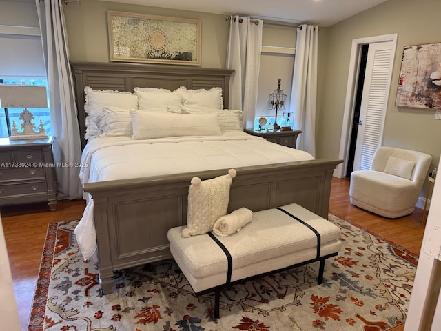 bedroom with wood-type flooring and vaulted ceiling